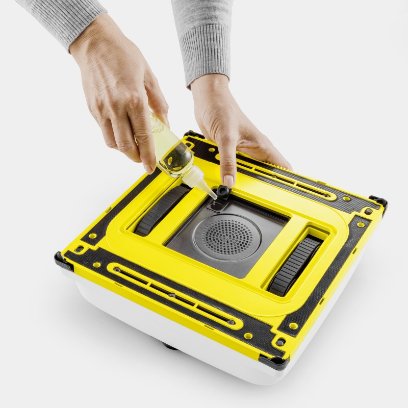 Osoba wlewa płyn z małej butelki do żółtego urządzenia czyszczącego.