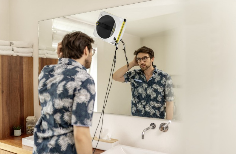 Mężczyzna w lustrze z czyścikiem do okien na szybie.