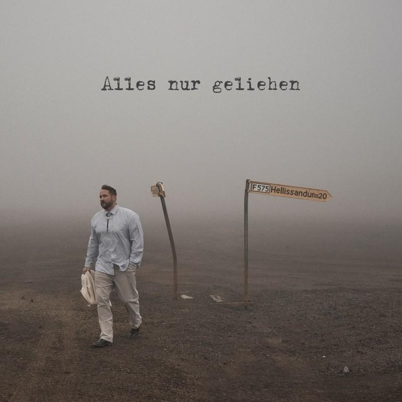 Mann geht im Nebel, Wegweiser F575 Hellissandur 20, Text oben.
