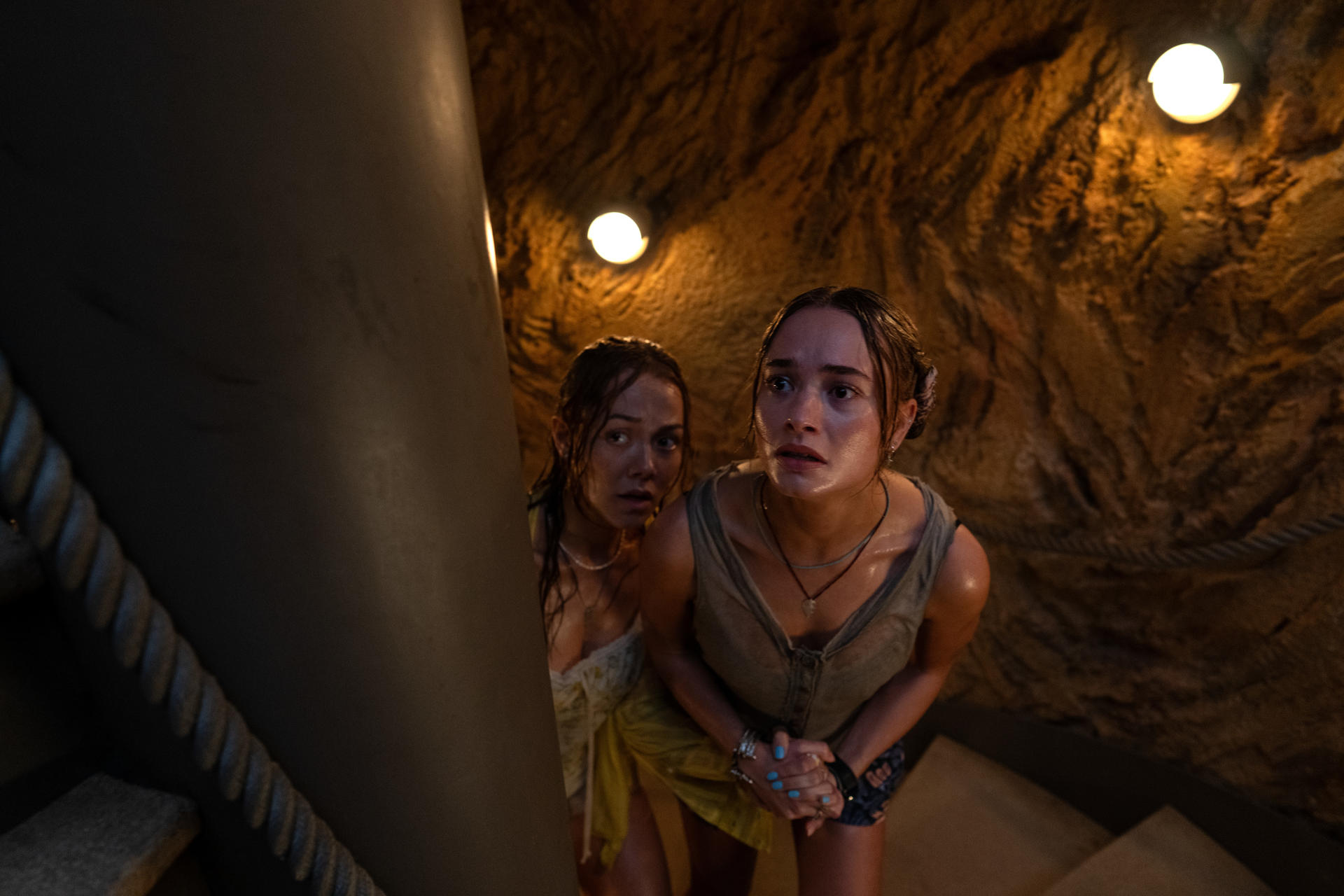Zwei Frauen in dunkler Höhle, eine blickt besorgt nach oben.