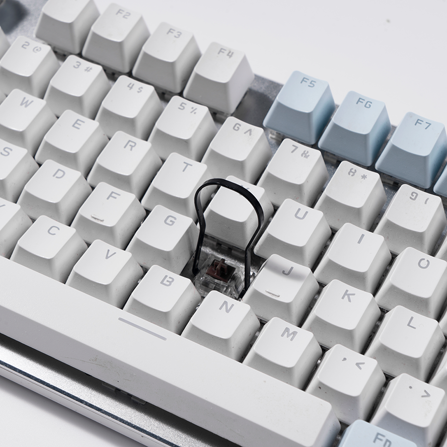 Eine weiße Tastatur mit hellblauen Funktionstasten. Ein Schalter ist sichtbar.
