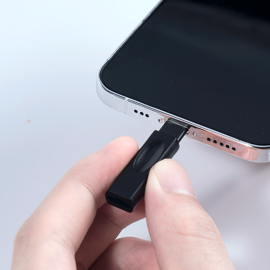Ein schwarzer Stecker wird in einen silbernen Smartphone-Anschluss gesteckt.