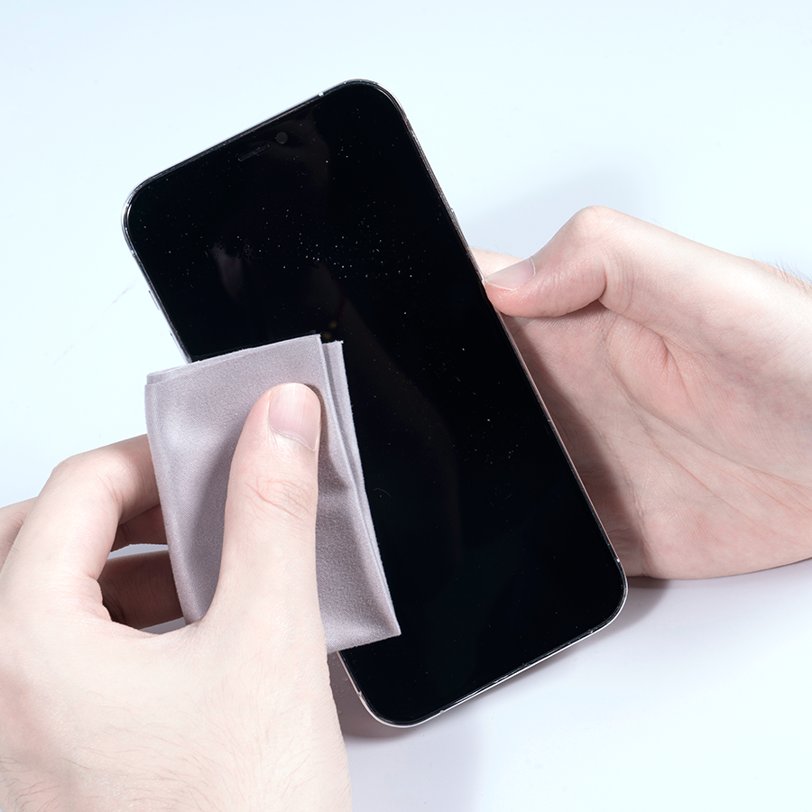Hände reinigen ein Smartphone-Bildschirm mit einem grauen Tuch.