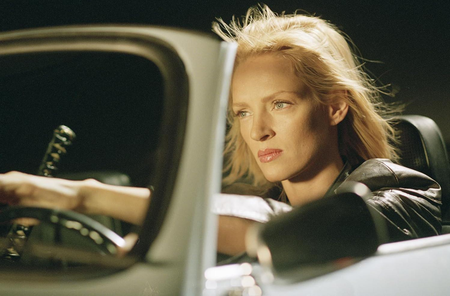 Eine blonde Frau fährt nachts Auto, ihr Haar weht im Wind.