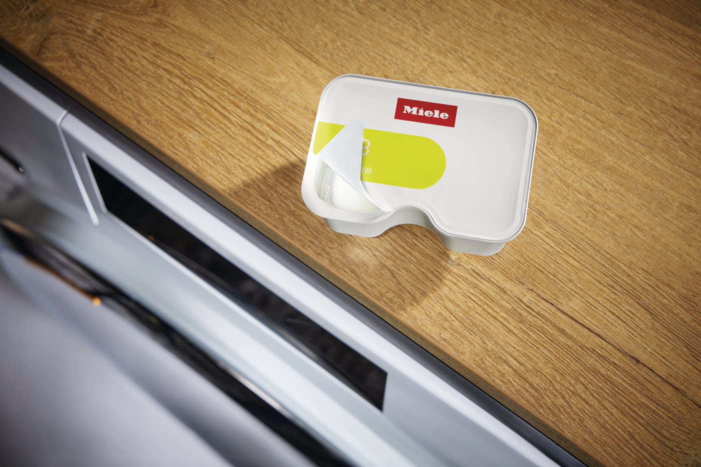 Miele Reiniger auf Holztisch mit offener Verpackung.