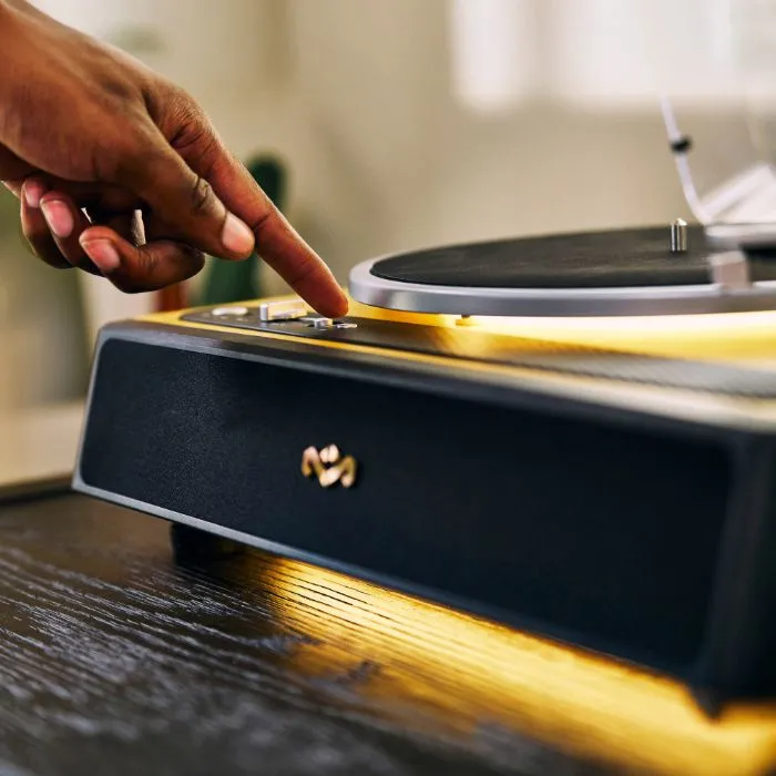 Egy kéz gombot nyom egy fa tokos lemezjátszón.