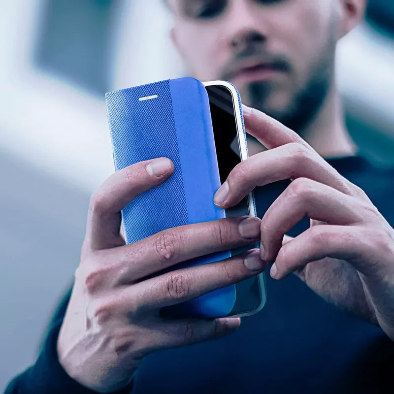 Férfi kék mobiltelefont tart védőtokkal a kezében.