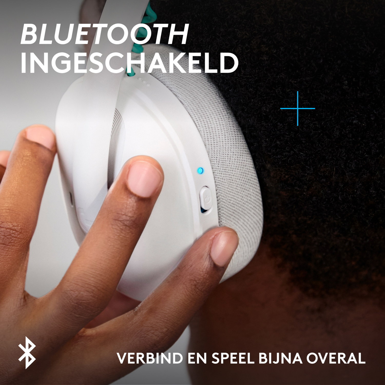 Close-up of a white headphone held by a hand, with text.