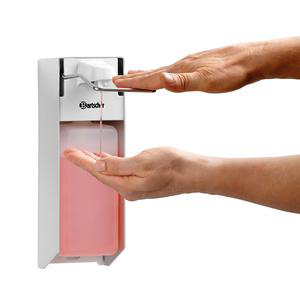 Eine Hand drückt einen Seifenspender, rosa Flüssigkeit tropft in die andere Hand.