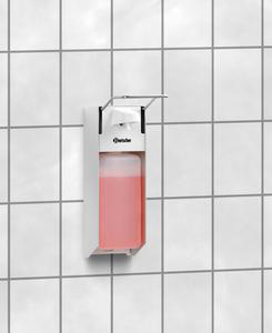 Ein weißer Seifenspender mit rosa Flüssigkeit an einer weißen Kachelwand montiert.