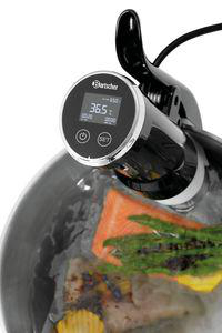 Ein Sous-Vide-Gerät mit digitaler Anzeige (36,5°C) über einem Topf mit Lachs und Spargel.
