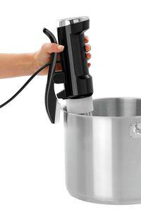 Hand hält schwarzen Stabmixer über Edelstahltopf.