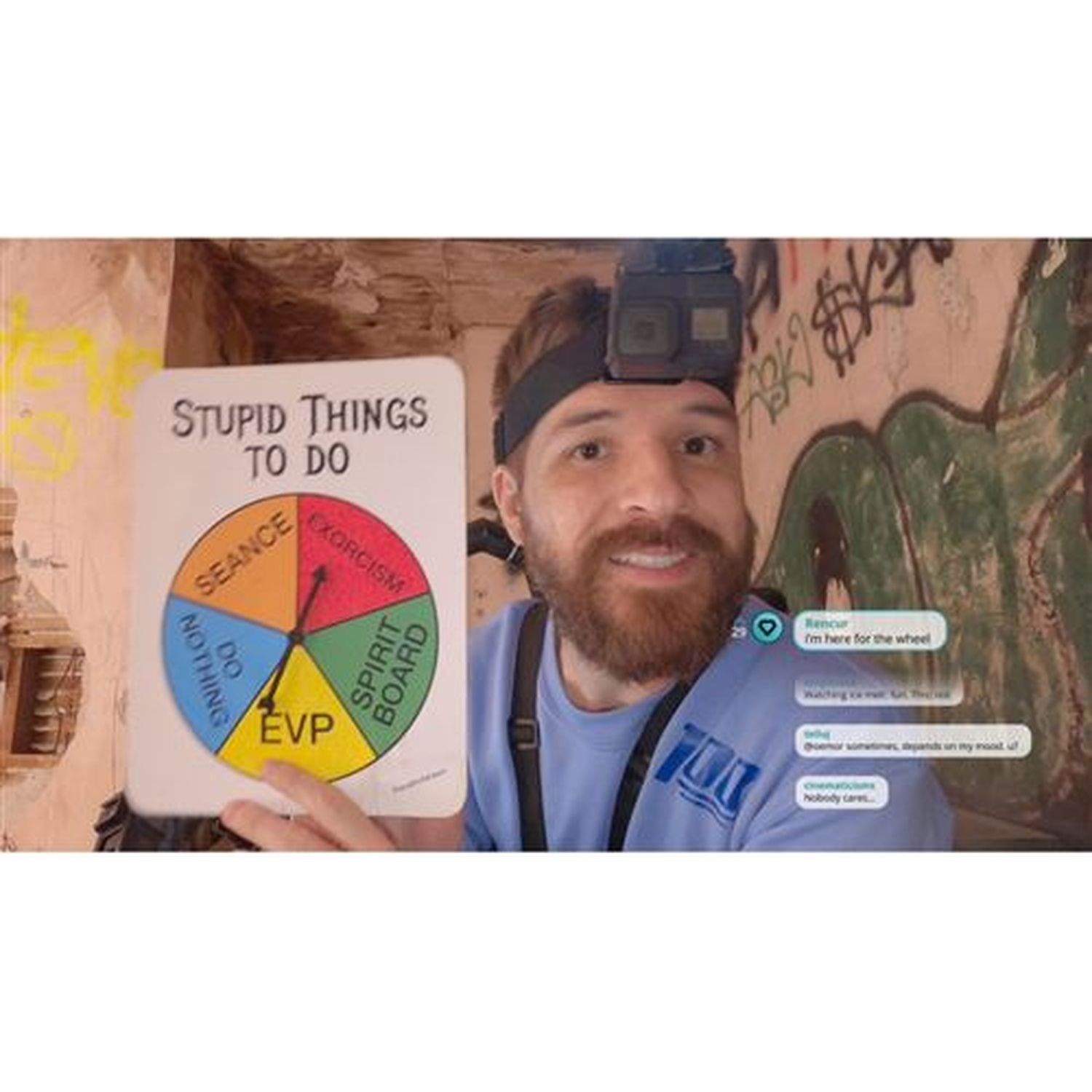 Een man met een camera op zijn hoofd houdt een rad van fortuin vast met 'Stupid Things to Do'.