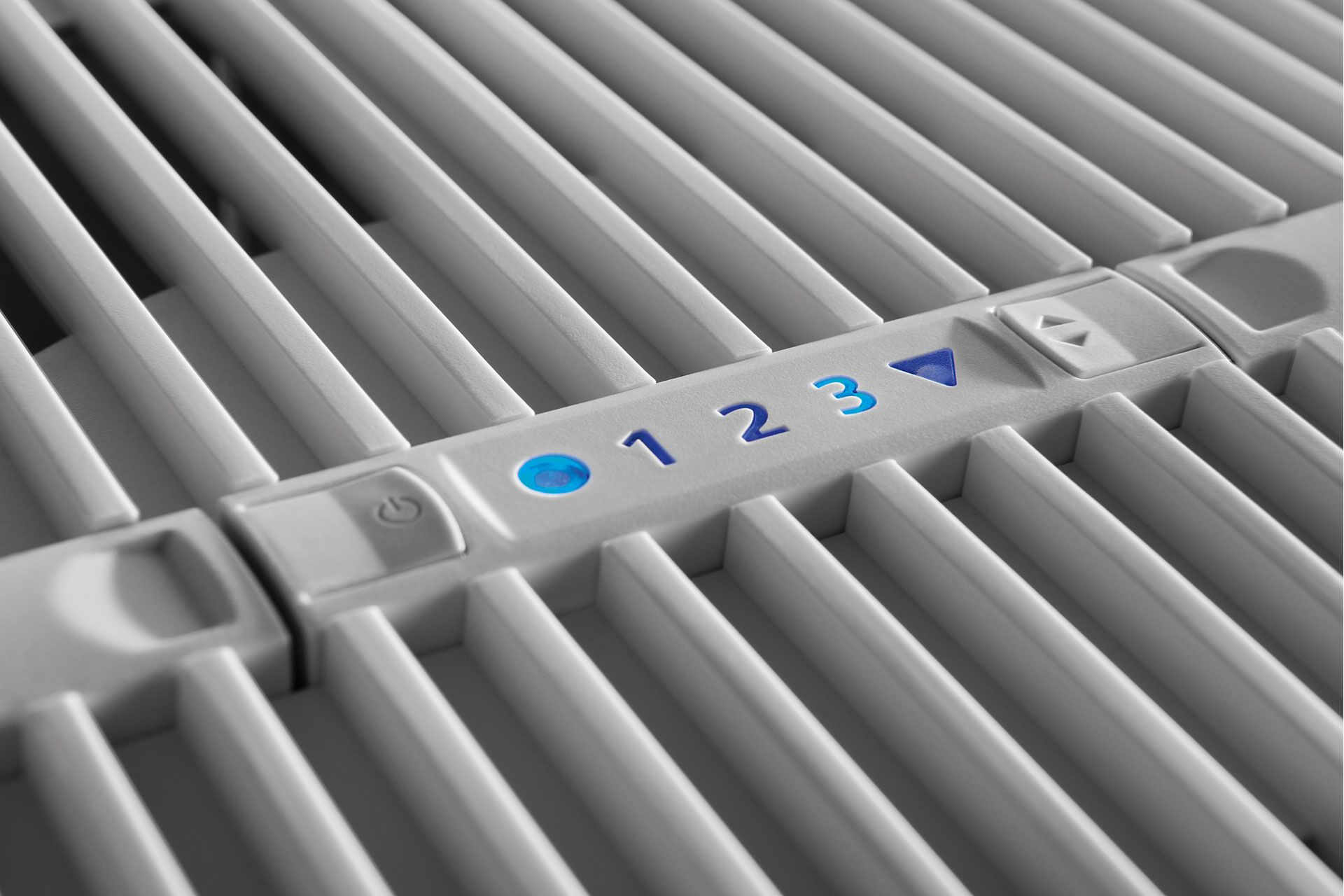Primo piano di una superficie di ventilatore grigia con numeri blu 1, 2, 3 e controlli.