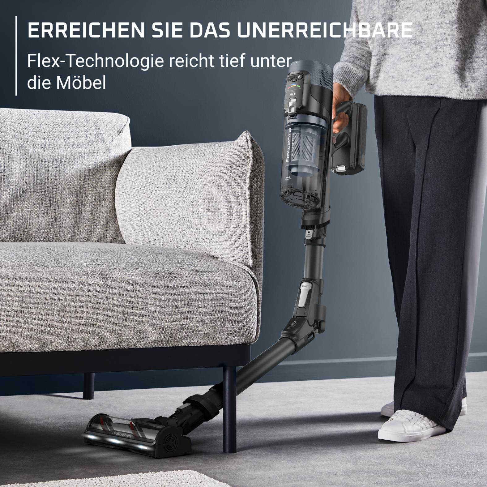 Ein Mann saugt unter einem Sofa mit einem flexiblen Staubsauger.