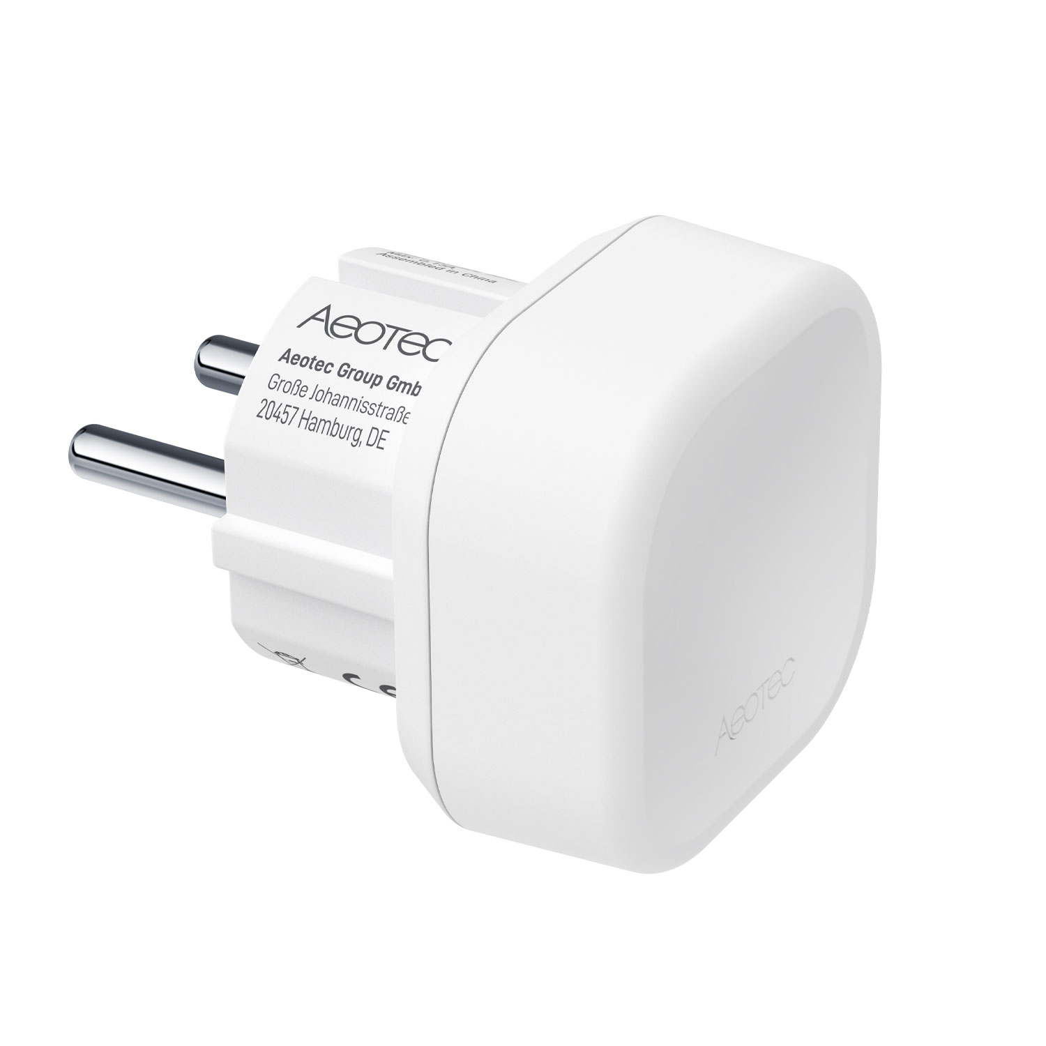 Ein weißer Steckeradapter von Aeotec mit zwei Metallstiften und Firmenadresse.