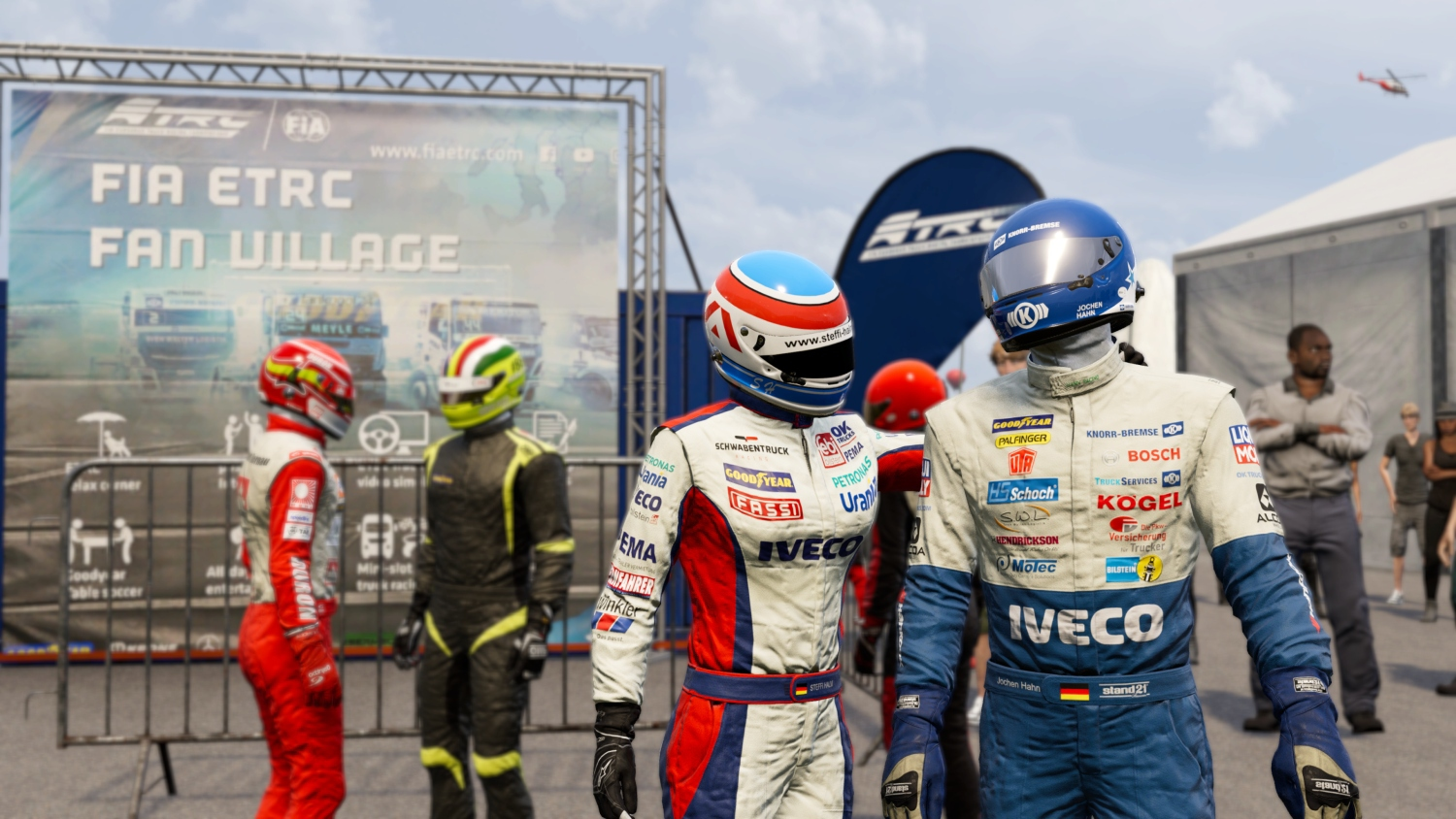 Piloti in tute colorate davanti a uno striscione FIA ETRC Fan Village e una bandiera blu.