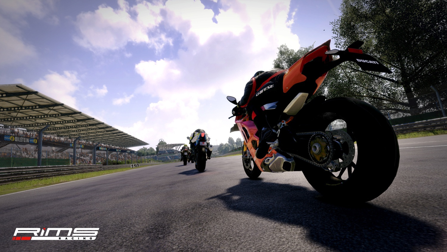 Des motocyclistes font la course sur une piste avec des tribunes et des arbres visibles.