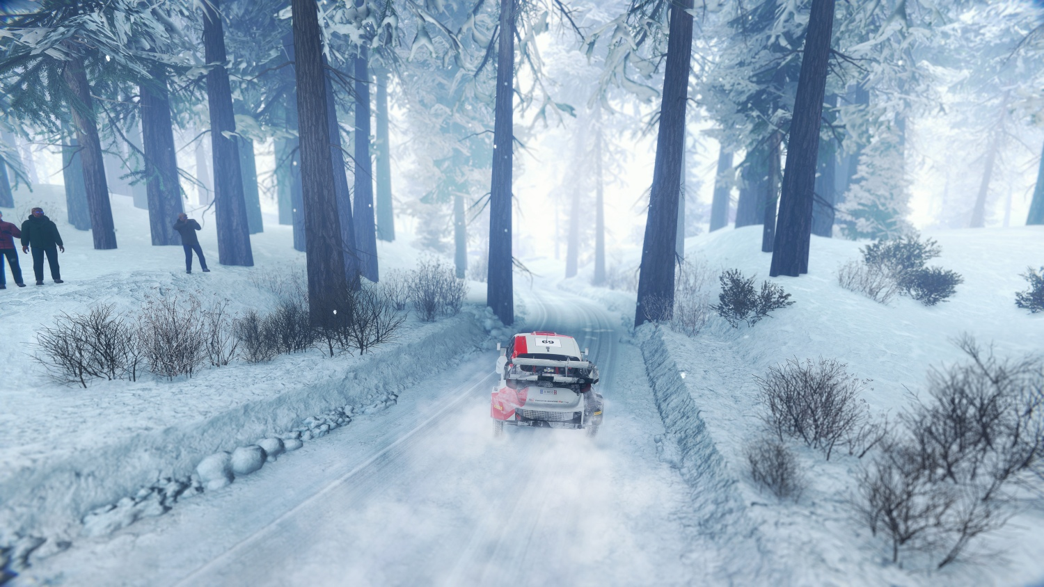 Ein roter Rallyewagen fährt auf verschneiter Straße durch einen Wald.