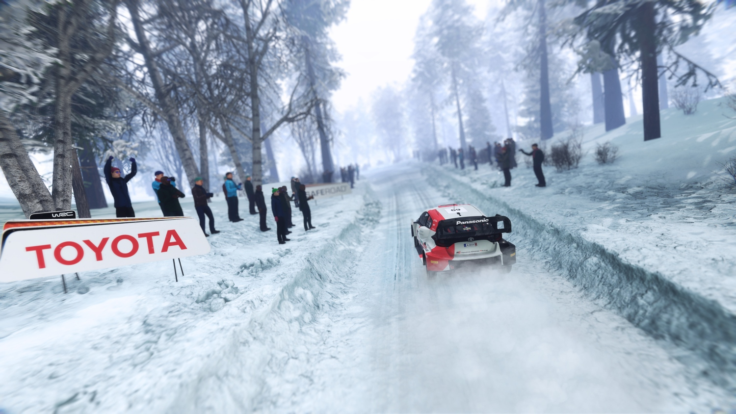 Ein Rallyeauto fährt auf einer verschneiten Strecke, Zuschauer stehen am Rand.