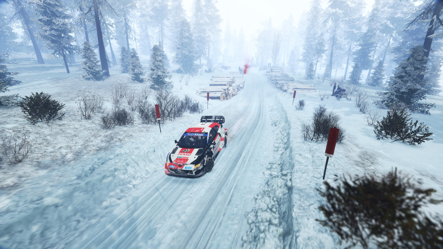 Ein Rallyewagen fährt auf einer verschneiten Straße durch einen Wald.