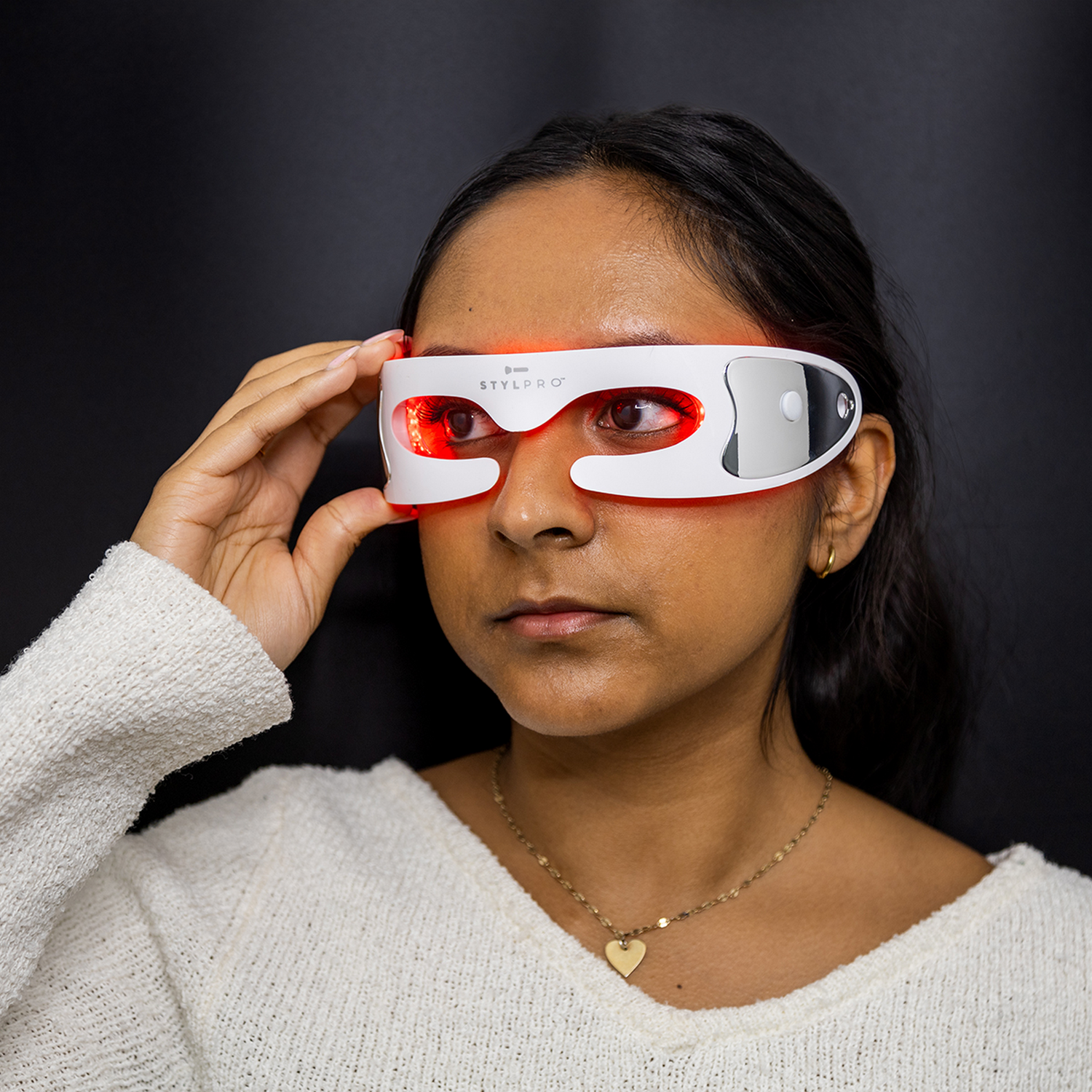 Mujer con máscara de ojos LED roja y suéter blanco.