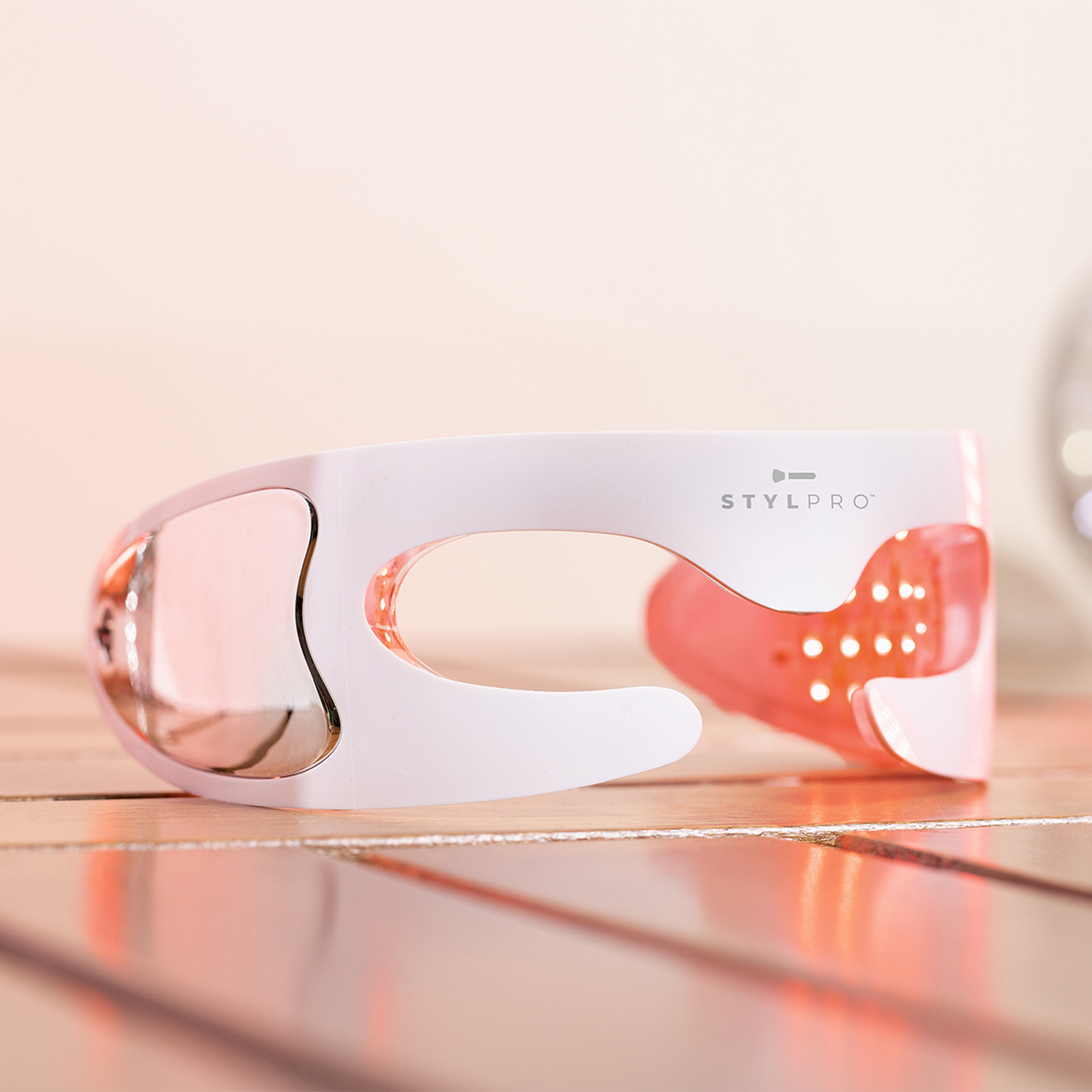 Un dispositivo Stylpro blanco con luces rojas sobre madera.
