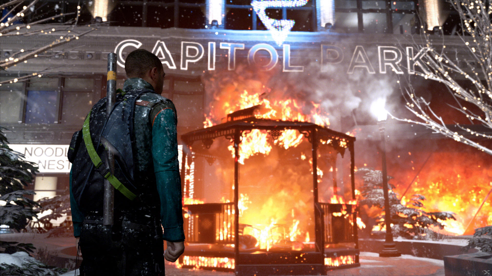 Mężczyzna z plecakiem patrzy na płonący budynek z napisem 'Capitol Park'.