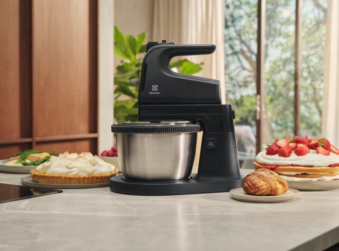 Czarny mikser ręczny z misą ze stali nierdzewnej na blacie obok ciast.