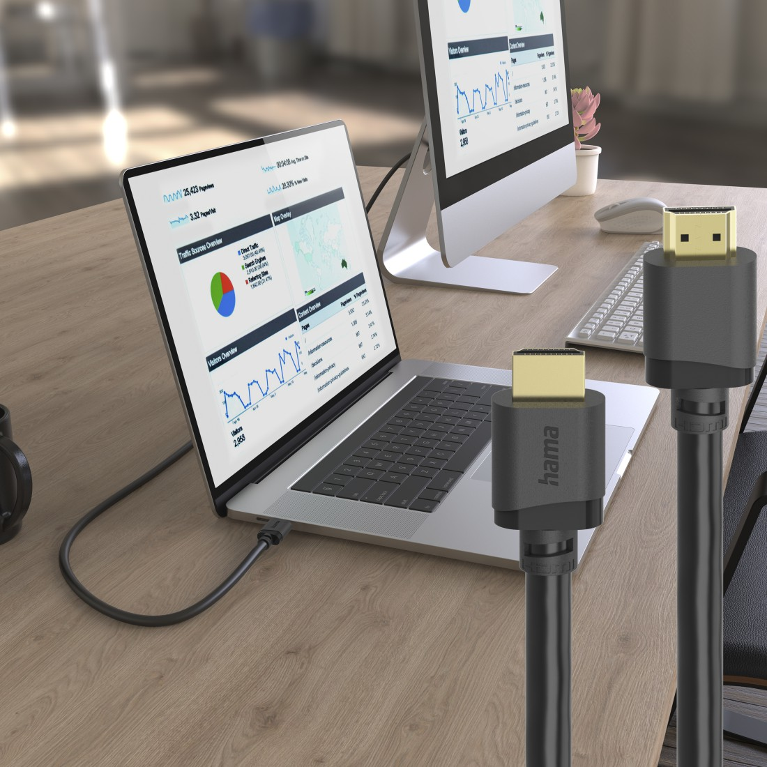 Laptop mit Analysedaten, Computer und HDMI-Kabel auf Schreibtisch.