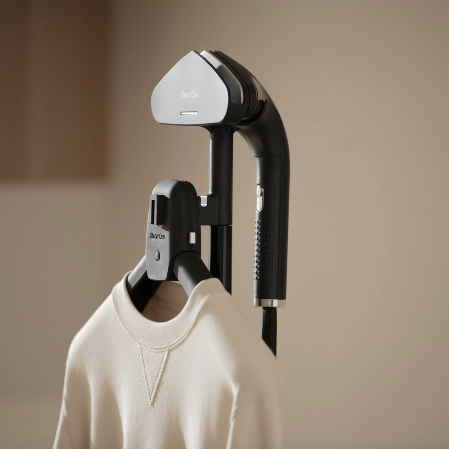 Een crèmekleurige sweater hangt aan een kledingstomer.