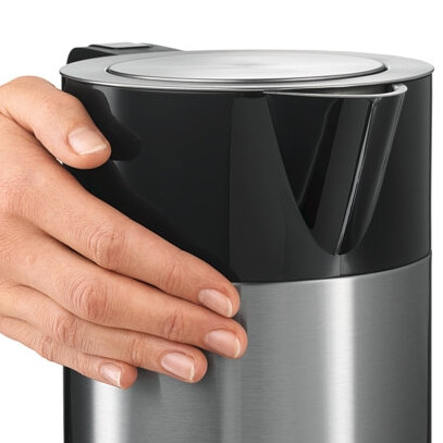 Dłoń trzyma czajnik elektryczny czarno-srebrny.