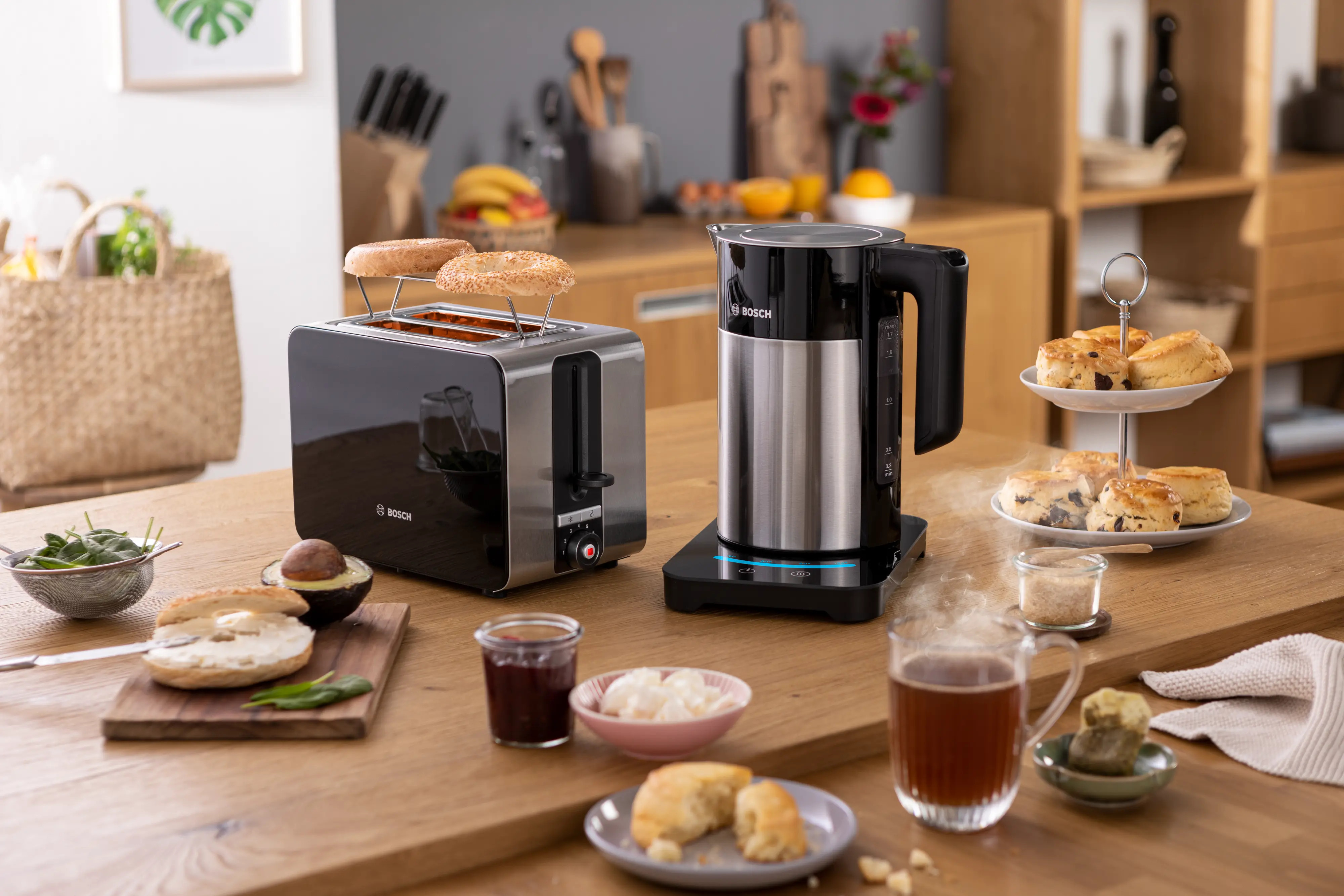 Toster z bajglami, czajnik, scones i herbata na drewnianym stole.