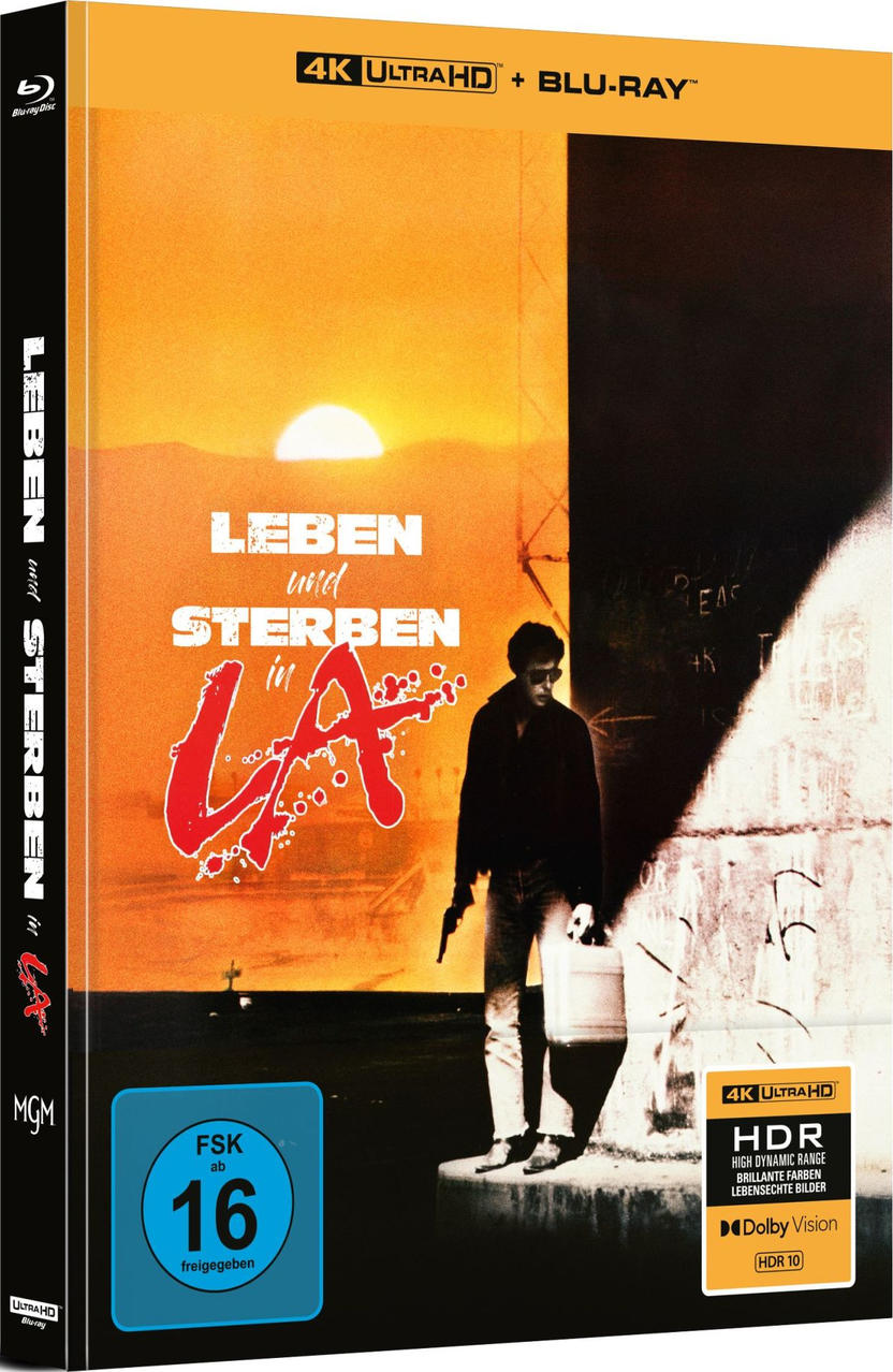 Ein Mann mit Waffe und Koffer vor einem Sonnenuntergang und Graffiti-Wand.