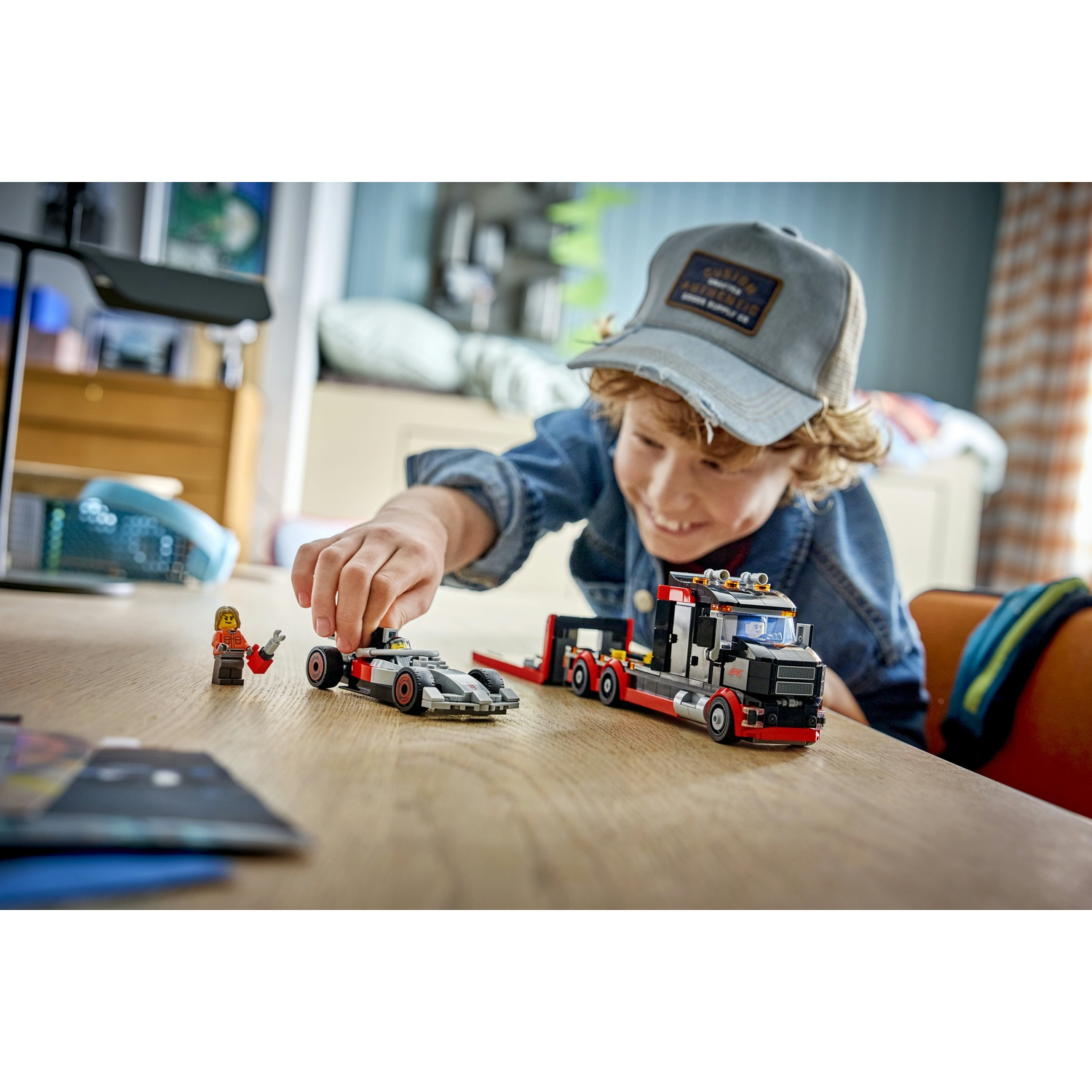 Un ragazzo gioca con auto Lego su un tavolo di legno. Una macchina da corsa.