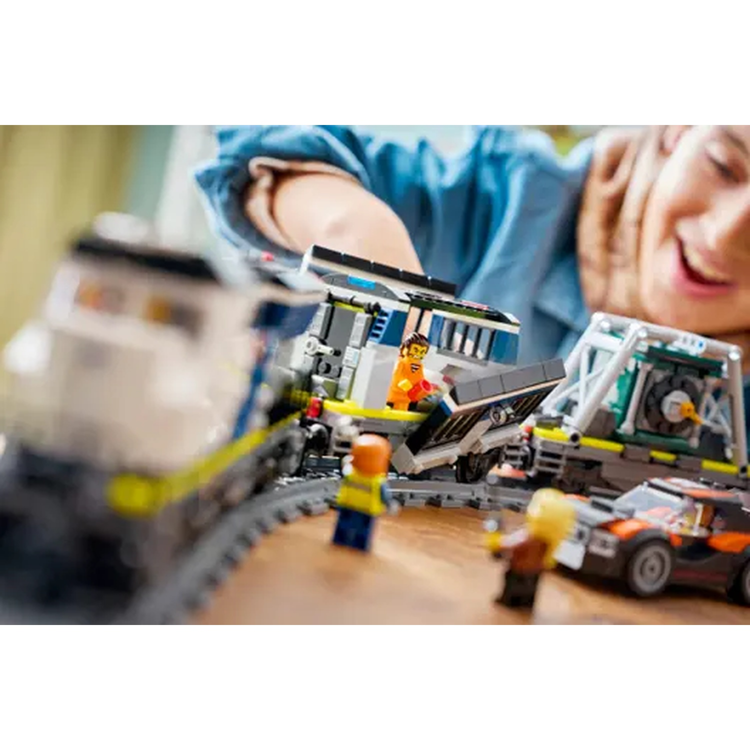 Bambini giocano con trenini, macchine e personaggi Lego su un tavolo di legno.