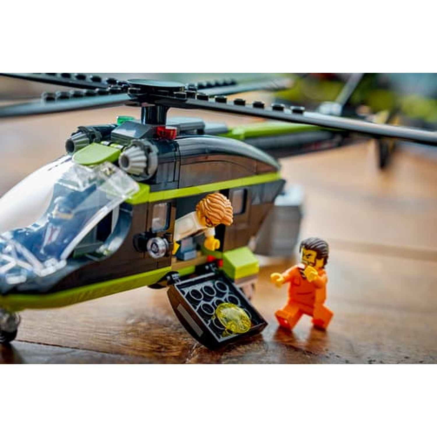 Un elicottero Lego con vano di carico aperto e due figure su una superficie di legno.