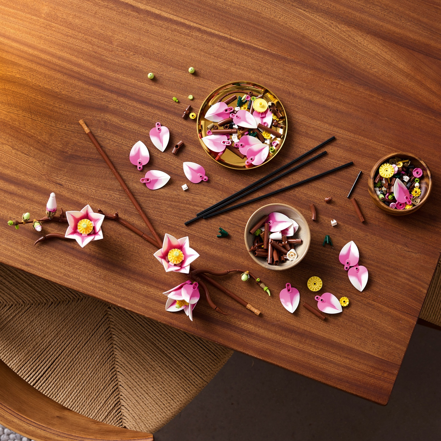 Parti di fiori su tavolo di legno: petali rosa, bastoncini, ciotole.