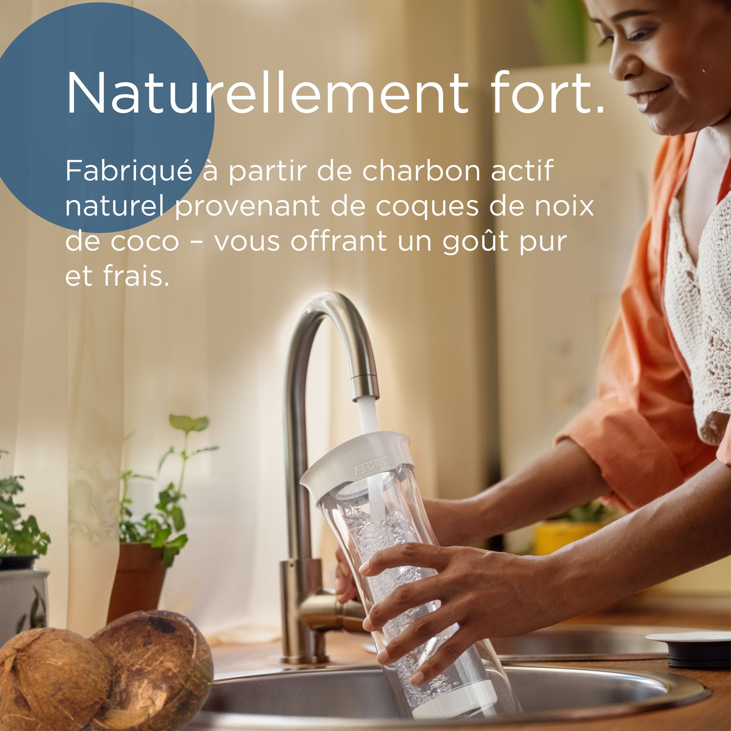 Woman fills a water filter under a faucet. Coconuts in the foreground.