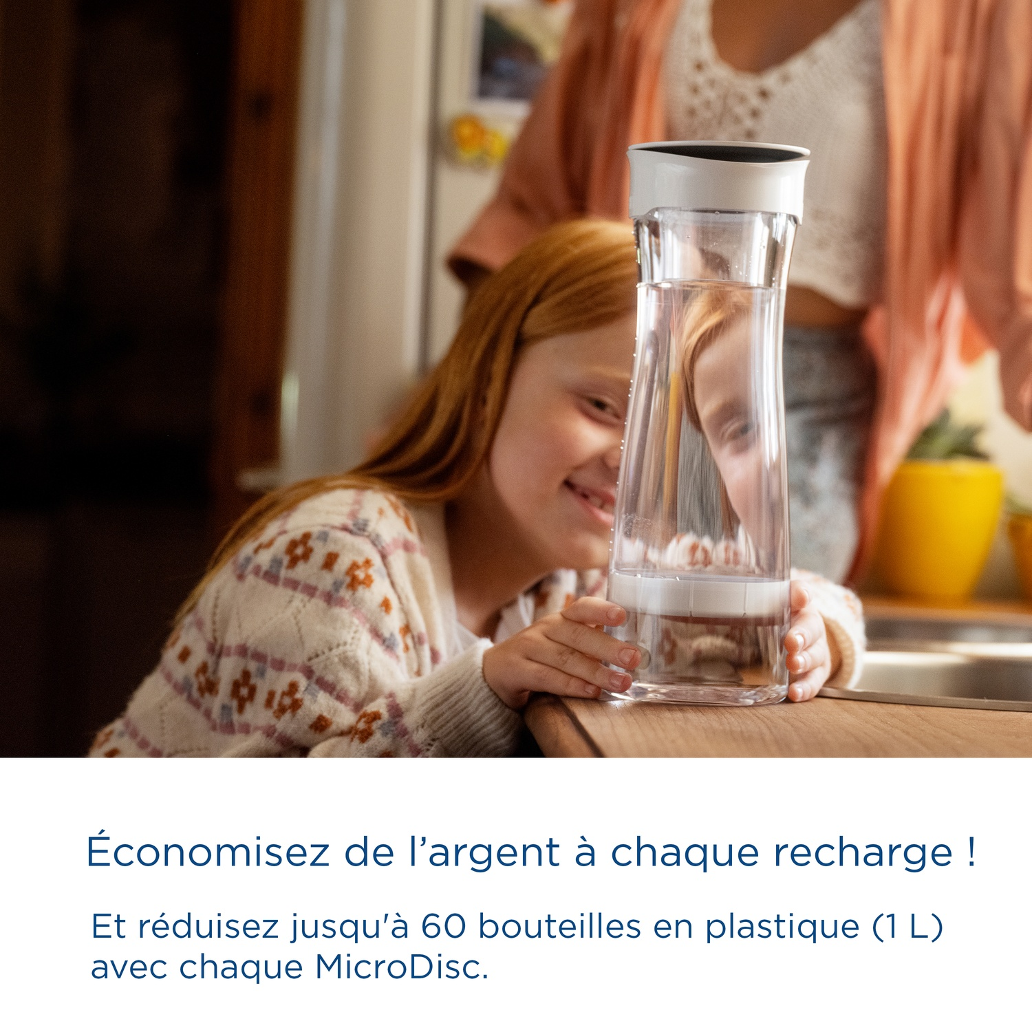 A girl looks into a water filter pitcher, a woman stands in the background.