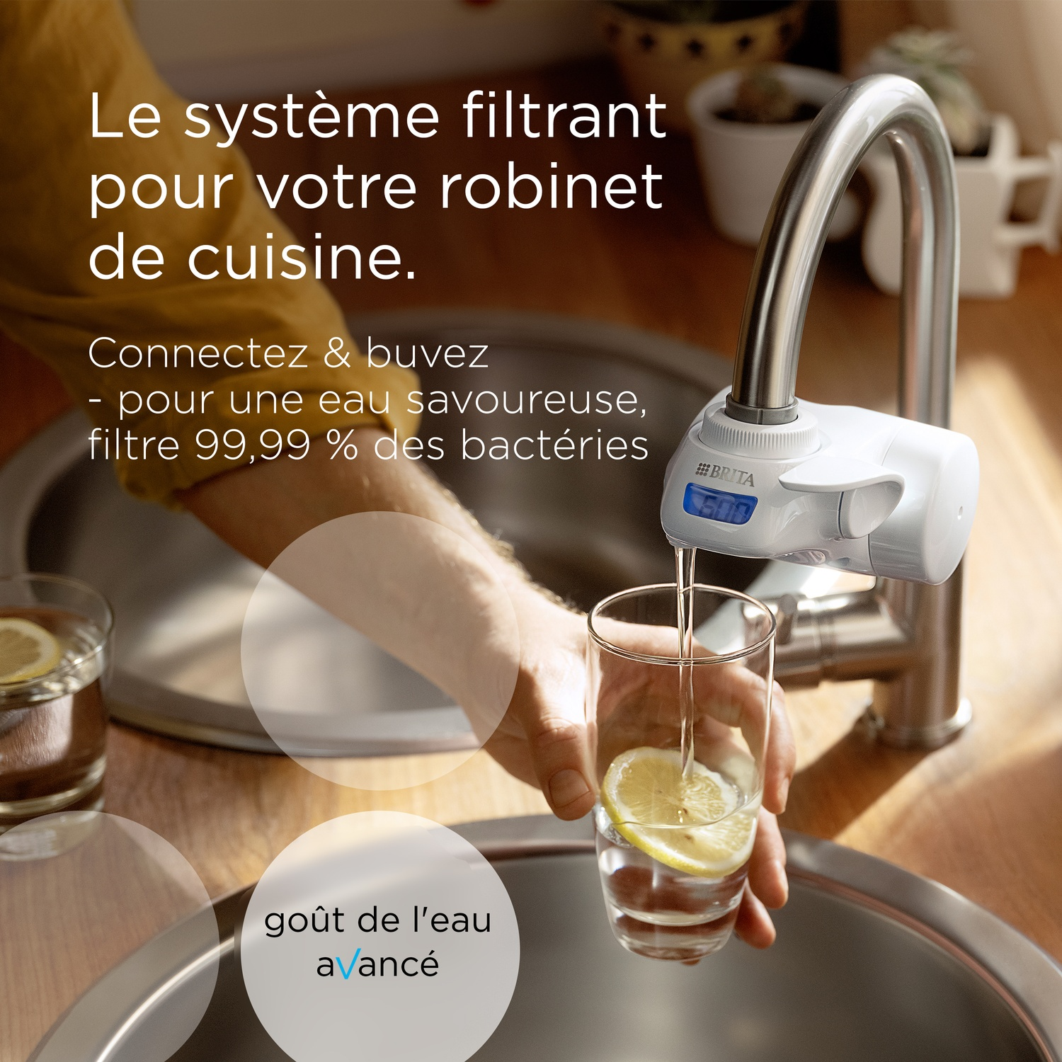 A faucet filter system fills a glass with a slice of lemon.
