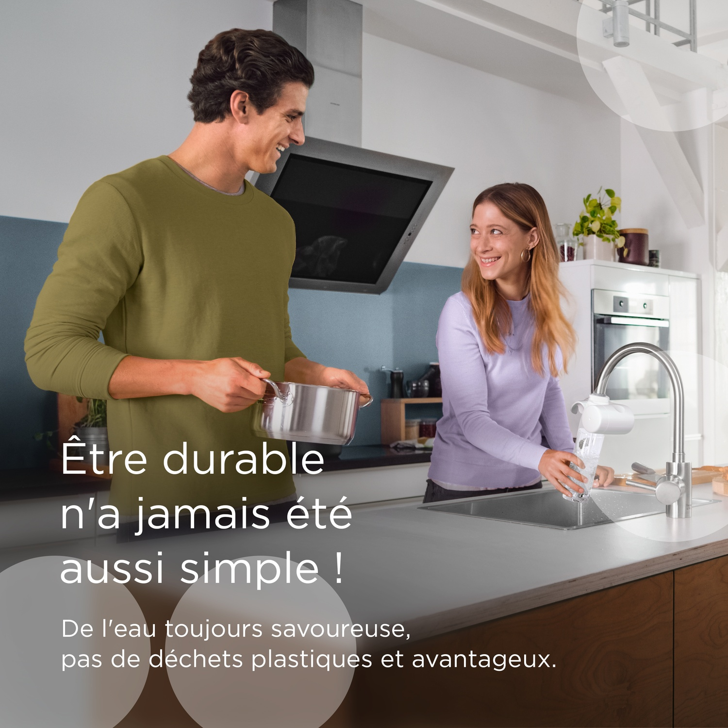 A man and woman in a kitchen. He holds a pot, she fills a glass with water.