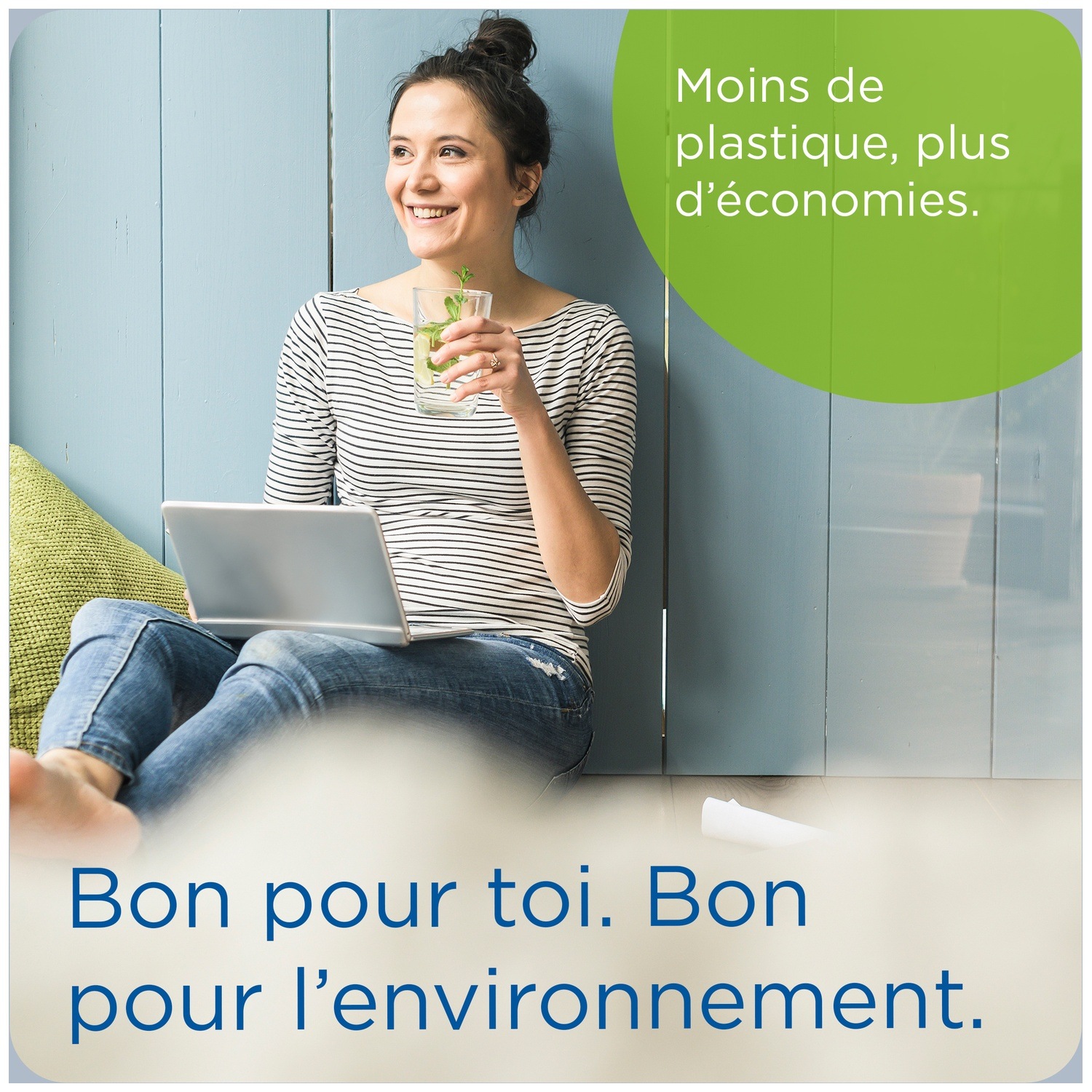 Woman with laptop and glass of water sits before blue wood panel. Less plastic, more savings.