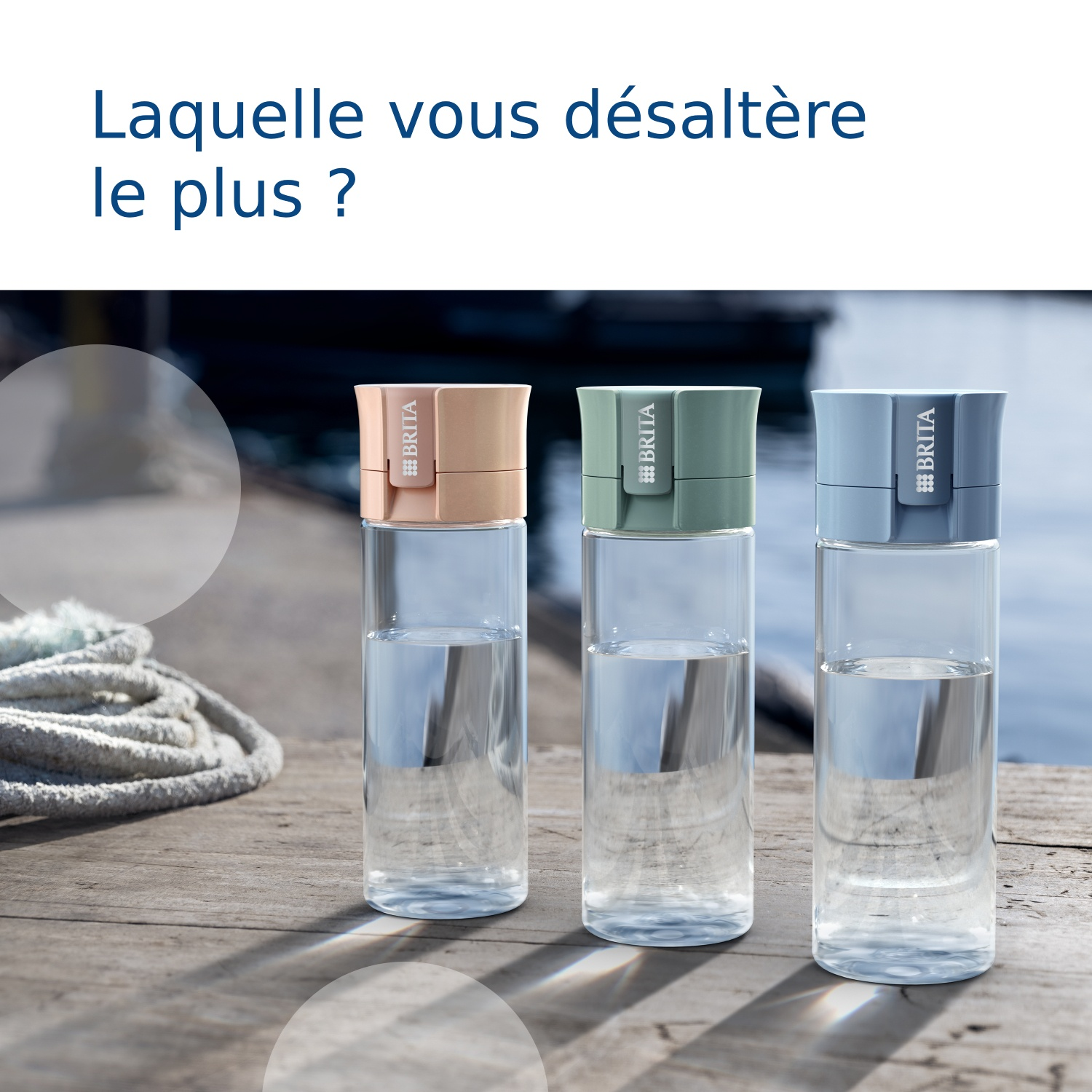 Drie Brita waterflessen in roze, groen en blauw op houten planken bij het water.