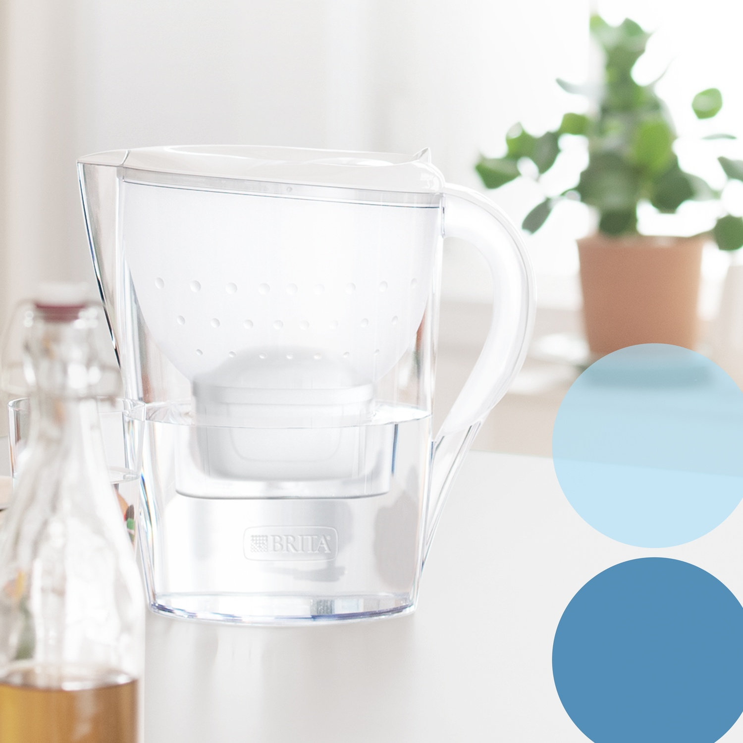 Een Brita waterfilterkan staat op een wit oppervlak met een fles op de voorgrond.