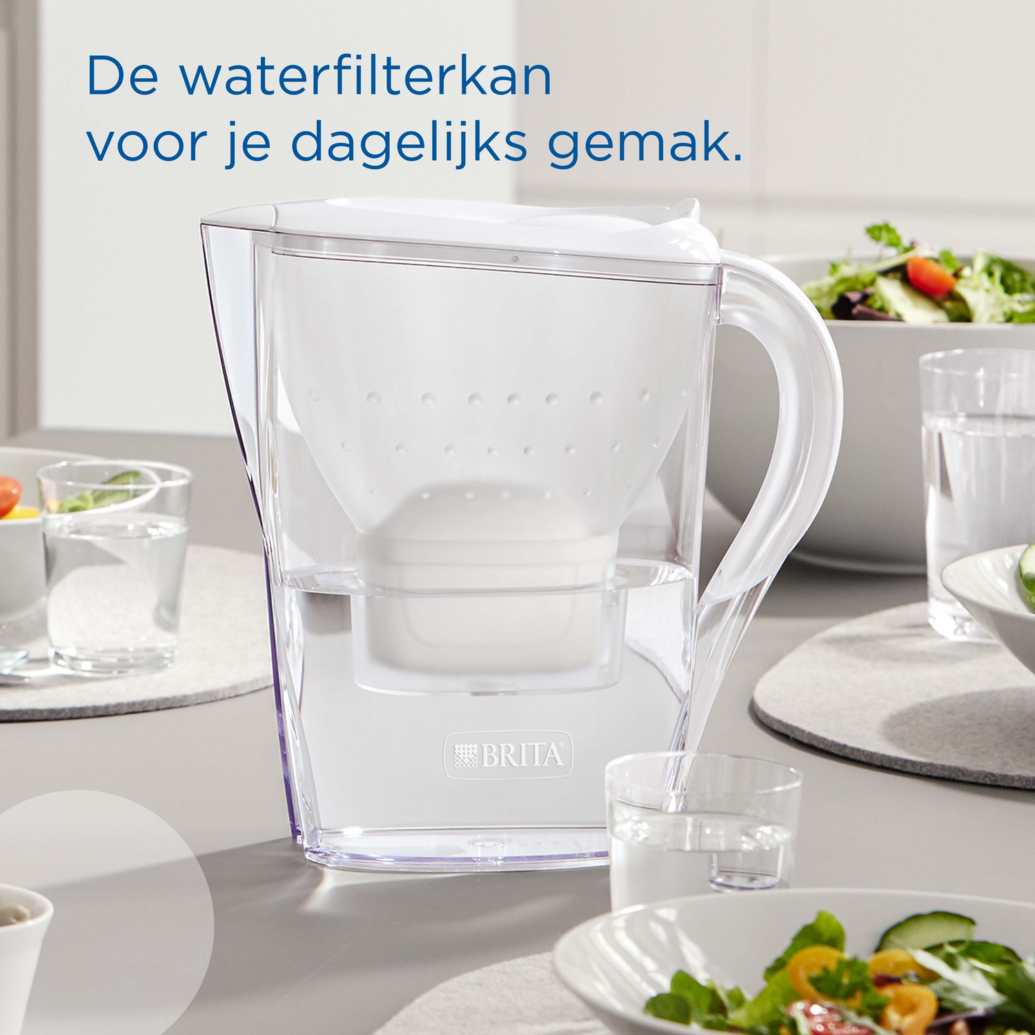 A white Brita water filter pitcher sits on a table with salad bowls.