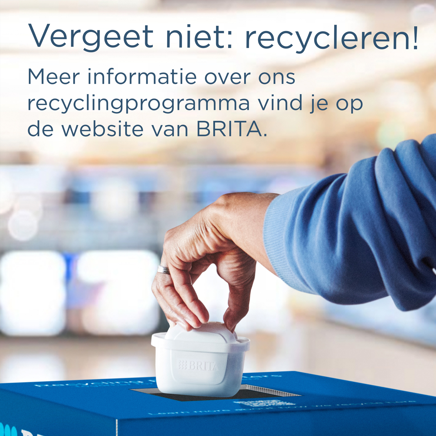 A hand places a BRITA filter into a blue recycling box.