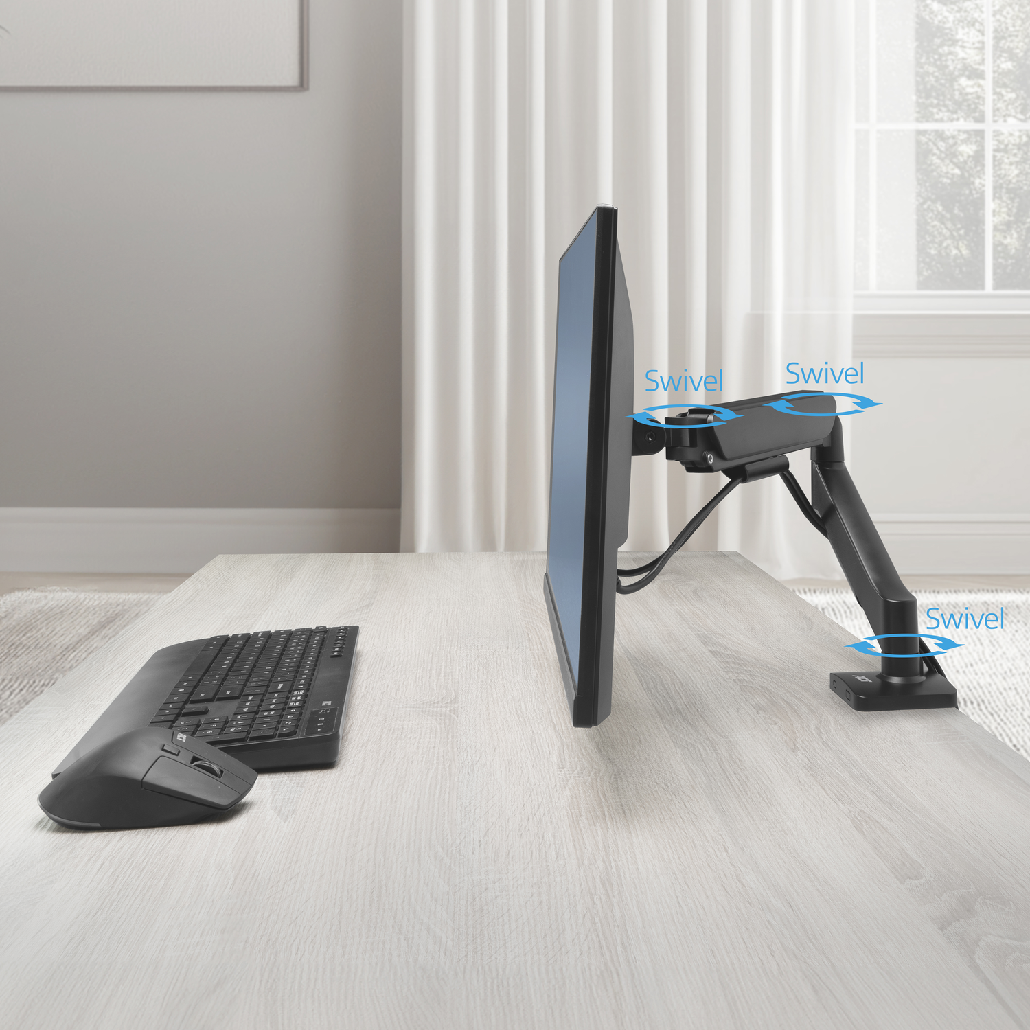 A monitor arm with keyboard and mouse on a wooden desk.