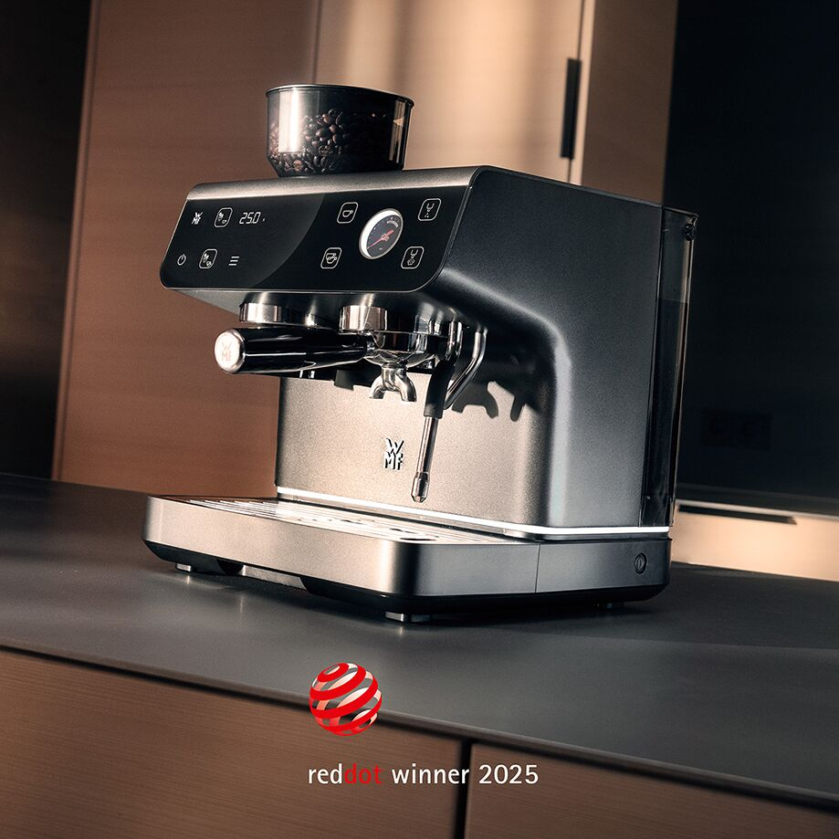 Eine silberne Espressomaschine mit Bohnenbehälter auf einer Arbeitsplatte.