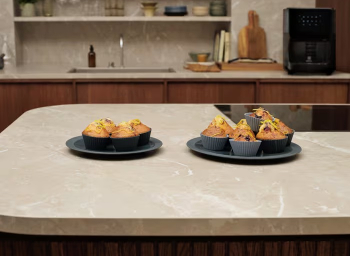 Dwa talerze z muffinkami na marmurowym blacie. Kuchnia w tle.